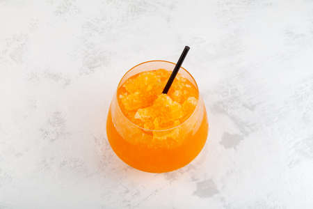 Glass of Orange Granizado on gray textured table, top view, selective focus. Traditional Spanish summer iced drink. Slushie fruit drink. Sweet Shaved Ice.の写真素材