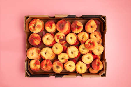 Fig peaches in paper box on pink background, top view. Croppeaches. Season fruits.