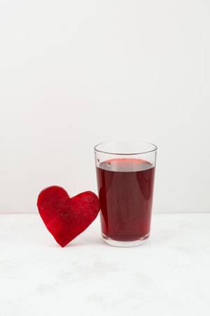Healthy drink with beetroot juice. Glass of red beverage. Slice of beet heart shaped. Fermented homemade drink.の写真素材