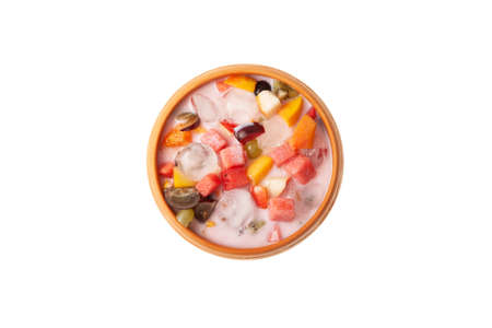 Es Campur or Es Buah isolated on white background, top view. Fruit soup with yogurt and shaved ice in clay bowl. Design elements for street cafe or restaurant. Popular indonesian fruits cocktail dessert.の写真素材