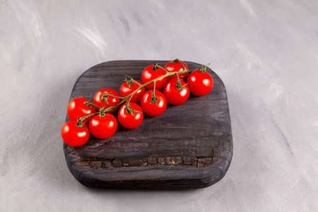 Cherry tomatoes on wooden board. Gray background, selective focus.の写真素材