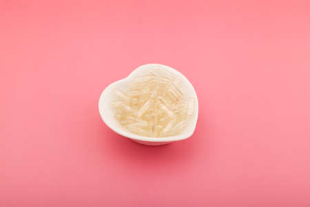 Natural Gelatin Empty Capsules in white bowl. Tablets for self-filling the required dose of medication or dietary supplements.の写真素材