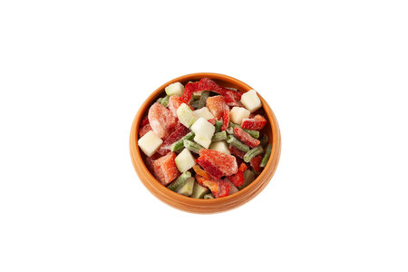 Different Frozen Vegetables in clay bowl on white background. Mexican mix. Concept - Freezing and proper defrosting of vegetables.の写真素材