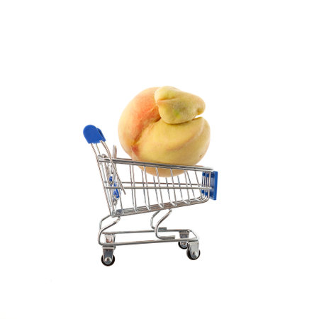 Ugly fruit concept. Deformed peach in trolley (shopping cart) on white background. design element. Reduce organic food waste. Last trend - Eating imperfect vegetables and fruits.の写真素材