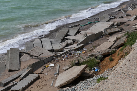 Seashore, destruction after storm. Destroyed concrete structures and staircases. Plastic garbage was...