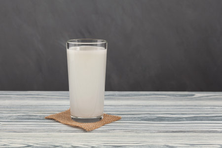Tibicos or Water kefir in tall glass on gray background. White muddy Fermented drink made with water and symbiotic culture of bacteria and yeasts. Healthy probiotic Tibi drink.の写真素材