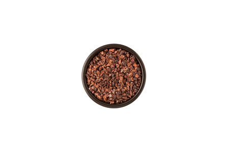 Cocoa nibs in ceramic dark bowl on white, top view. Sugar-free product, Natural antidepressant. Crushed cocoa beans of weak roasting often added to cereals, smoothies, desserts, and drinks.の写真素材