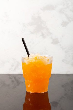 Orange Granizado with Yuzu juice in disposable take away plastic cup. Refreshing Slushie drink. Iced fruit drink. Sweet citrus Shaved ice.の写真素材