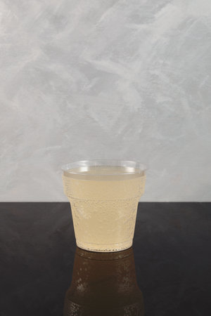 Pomada drink in disposable plastic cup on gray background. Refreshing iced cocktail with gin and lemonade.の写真素材
