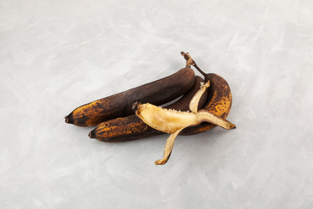 Brown fermented bananas for baking vegan banana bread. Rotten expired fruits. Ugly bananas on gray background.の写真素材