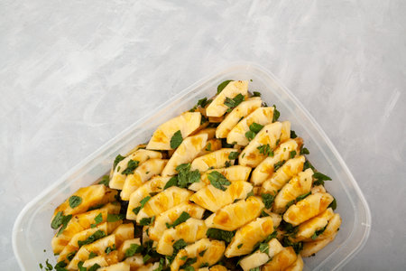 Traditional Asian fruit salad. Fermented Pineapple slices with mint leaf in cane sugar syrup. Sweet Pineapple dessert in plastic container on gray background. Selective focus, copy space.の写真素材