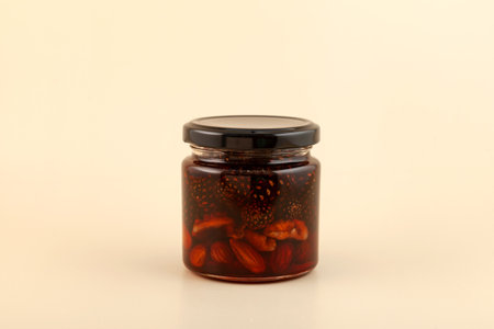 Jam with pine cones, almond nuts and walnuts in glass jar. Healthy syrup to support the immune...