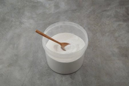 Succinic acid or dicarboxylic acid in plastic container on gray background. Food additive E363. Spirit of amber, white powder, used as acidity regulator in the food and beverage industry.の写真素材