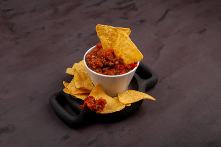 Chili con carne. Tex-mex food. Traditional Mexican spicy dish with red beans, peppers, tomatoes and minced meat. Delicious spicy Chili con carne with tortilla corn chips.の写真素材