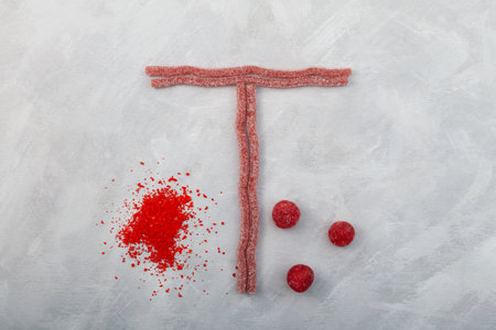Heap of Food coloring Tartrazine and chewing sweets in form letter T on gray background. Pigment E102. Concept of hazardous food additives in food industry.の写真素材