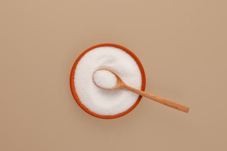 Xylit powder or birch sugar in plate with spoon, top view. Food additive E967, sweetener. Xylitol is used as sugar substitute in drugs, dietary supplements, confections, toothpaste, and chewing gum.の写真素材