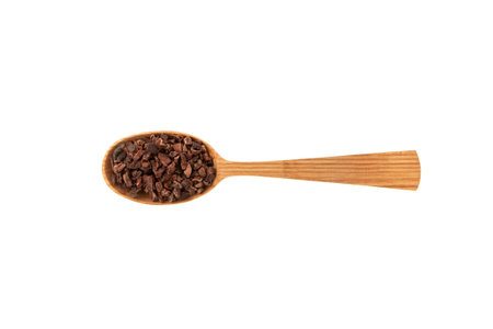 Cacao nibs in wooden spoon on white background. Sugar-free product. Natural antidepressant. Crushed cocoa beans of weak roasting. Good chocolate chip alternative.の写真素材