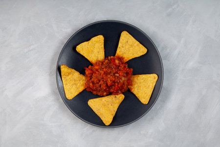 Chili con carne with tortilla corn chips on dark plate, top view. Traditional Mexican food, spicy dish with red beans, peppers, tomatoes and minced meat.の写真素材