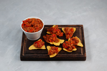 Chili con carne with tortilla corn chips on brown wooden cutting board. Tex-mex food. Traditional Mexican spicy dish with red beans, peppers, tomatoes and minced meat.の写真素材