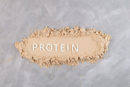 Heap of Pure Whey Protein Powder on gray textured background, top view. Inscription PROTEIN. Food additive promotes the growth of muscle tissue, used for healthy smoothies and fitness drinks.の写真素材