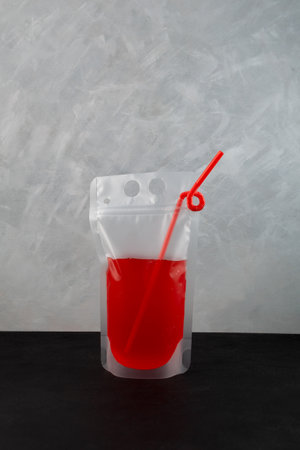 Spill-proof disposable drink pouch with red berry lemonade or wine slushy. Refreshing summer take away drink.の写真素材