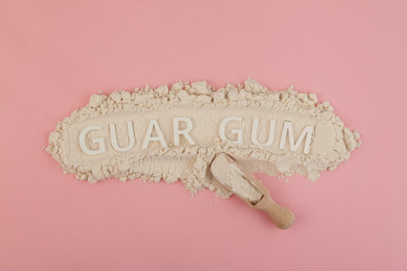 Guar gum powder or guaran with Inscription GUAR GUM. Food additive E412 in wooden scoop. Design element. Thickening agent. Stabilizer and Fat Replacer widely used in food industry.の写真素材