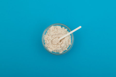 Guar gum powder or guaran in glass bowl with plastic measuring spoon top view. Food additive E412. Thickening agent. Guar Gum is widely used in dairy products. Texture improver and improves creaminess.の写真素材