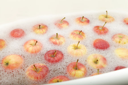 Apples washed in water with soap foam. Ripe apples swimming on water surface. Washing fruits in basin.の写真素材