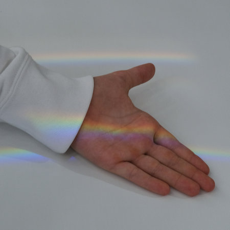 Rainbow light as diffraction on a child palm. Touching the rainbow.の写真素材