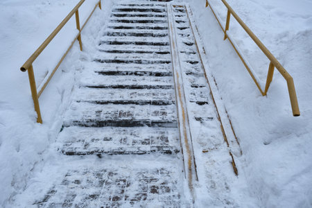 Slippery stairs on the street in winter. The problem of ascent and descent for baby carriage, elderly people, wheelchairs and people with limited mobility.の写真素材