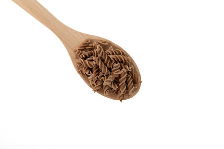 Pasta in wooden spoon, close-up. Design element. Flaxseed gluten free pasta. Fusilli made from flax and corn flour. Low glycemic index food.の写真素材