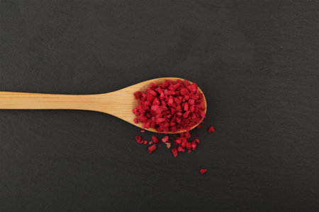 Dried freeze dried raspberries in wooden spoon on black background. Dehydrated raspberry nibs. Clever storage food.の写真素材
