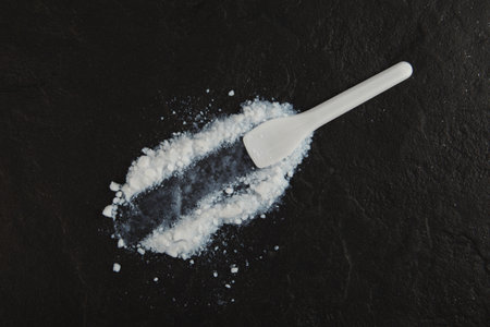Colloidal silicon dioxide and plastic spatula on dark stone surface. Food additive E551. Enterosorbent. Silicon dioxide powder or Silica is used in medicine and food industry.の写真素材
