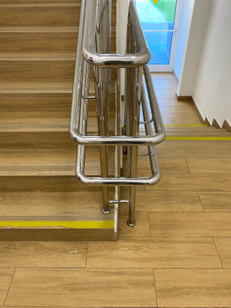 Modern comfortable handrails with handrails at different heights. Flight of stairs, steps with yellow warning stripe.の写真素材