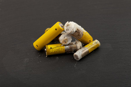 Used batteries with expired shelf life. Old oxidized and leaking batteries, leakage of alkaline electrolyte. Dangerous caustic white powder. Problems of electronic waste recycling.の写真素材