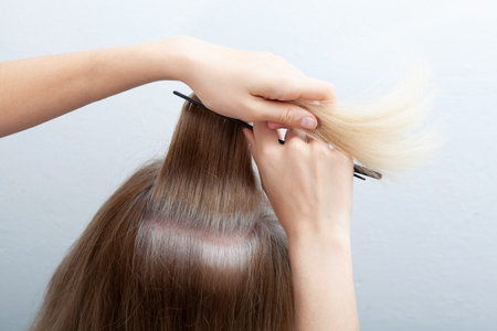 Going gray in young woman shows her gray hair, hair roots getting gray. Problem of early graying, pigmentation changes. Mental health, stress.の写真素材