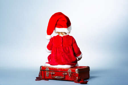 Rear view of child with Santa cap sitting on suitcase with giftsの写真素材