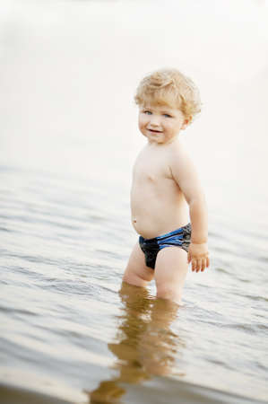 little funny boy playing in summer lakeの写真素材