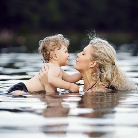 beautiful young mother with son in waterの写真素材