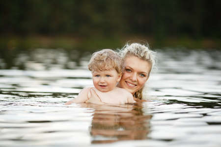 beautiful young mother with her son in waterの写真素材