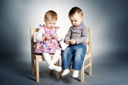 little boy and girl playing with mobile phonesの写真素材