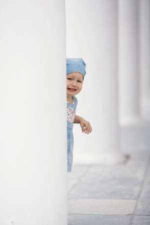 little girl hiding in white columnsの写真素材