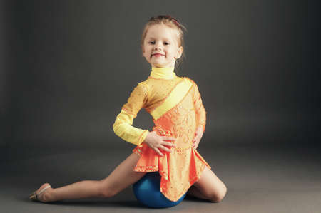 Beautiful girl gymnast with a ball on dark backroundの写真素材