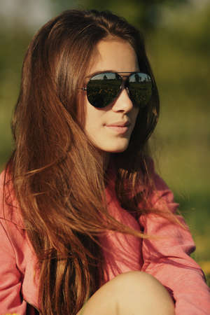 beautiful young girl with sunglasses in dandelion fieldの写真素材