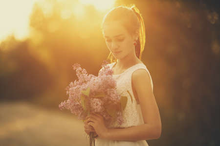 girl with bouquet of lilac in the rays of the evening sunの写真素材