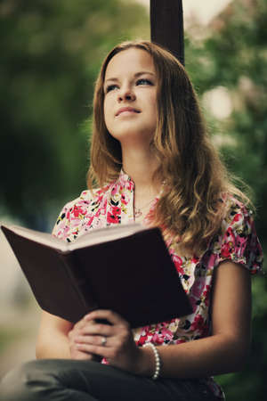 beautiful girl reading book sitting on the porch of  houseの写真素材
