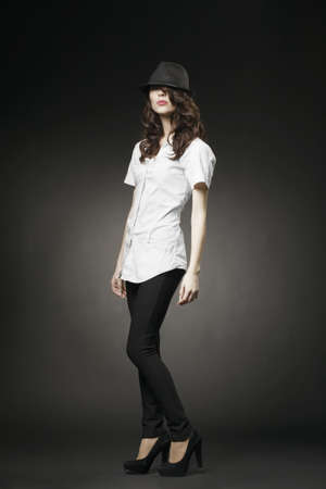 Beautiful brunette with black classic hat on dark backgroundの写真素材