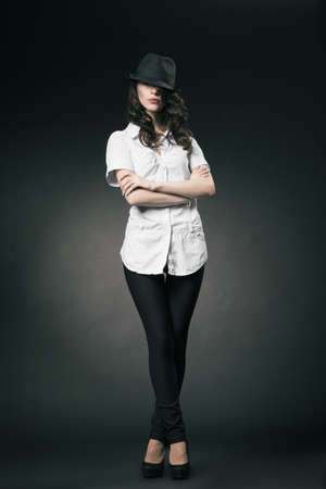 Beautiful brunette with black classic hat on dark backgroundの写真素材