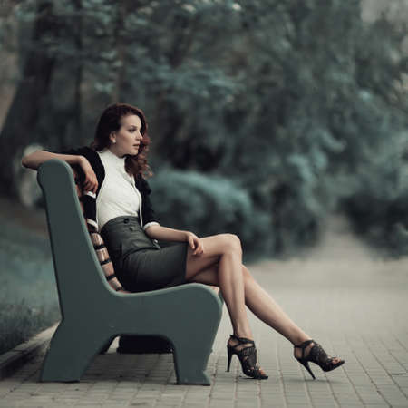 young beautiful girl sitting on bench in parkの写真素材