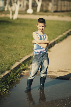 little happy boy standing in puddleの写真素材